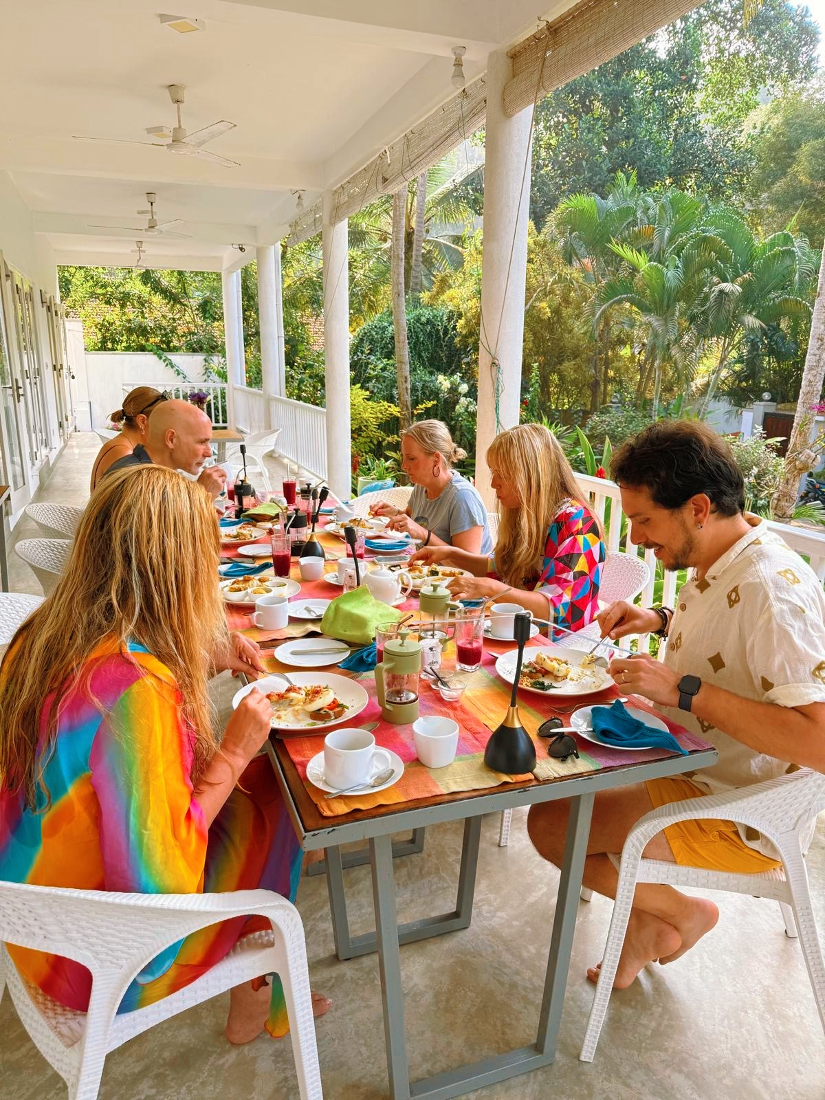 Guests sharing a long breakfast on a tropical veranda with colourful table settings